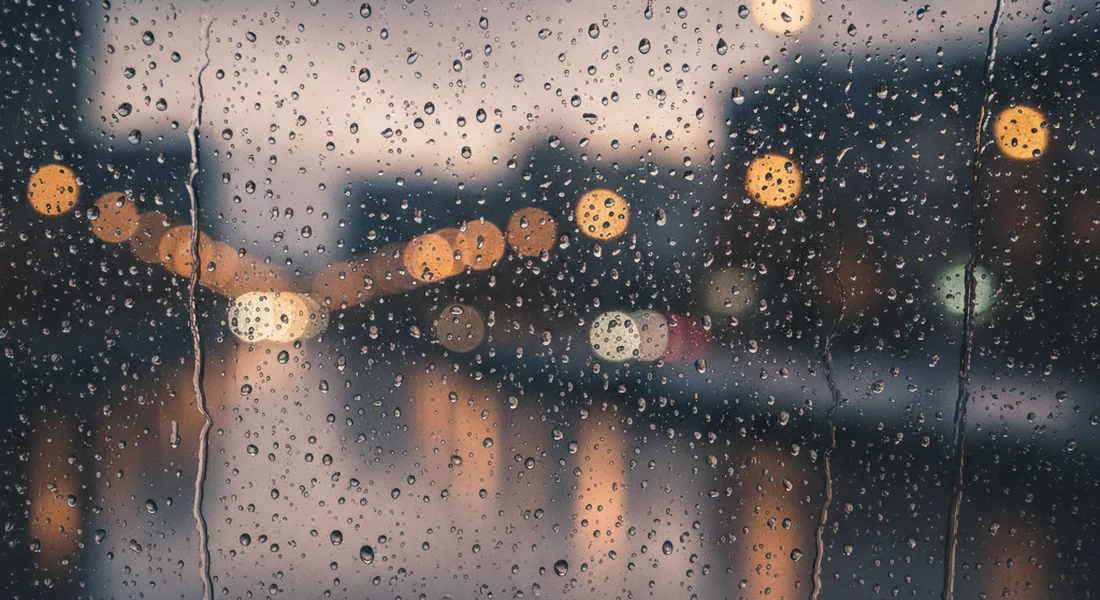 Rain on a window with soft blurred warm light behind it